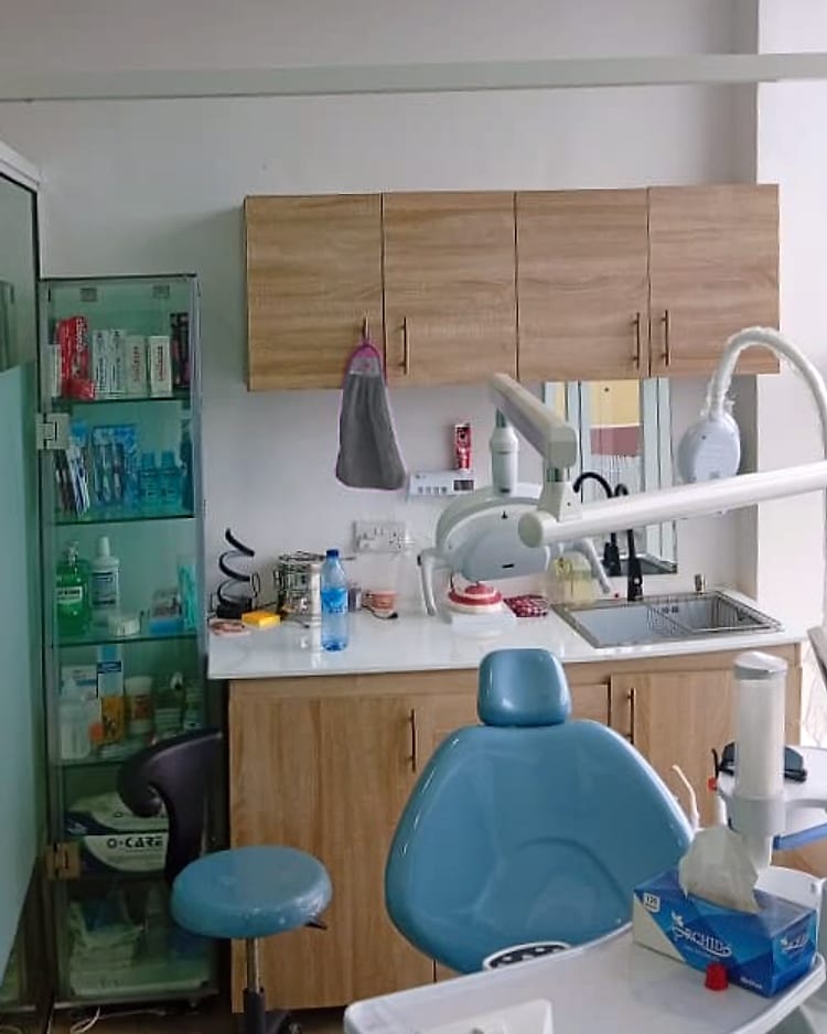 A blue dental chair and stool in front of wooden cupboards and a sink, in Surgery 2 at Vinix Dental